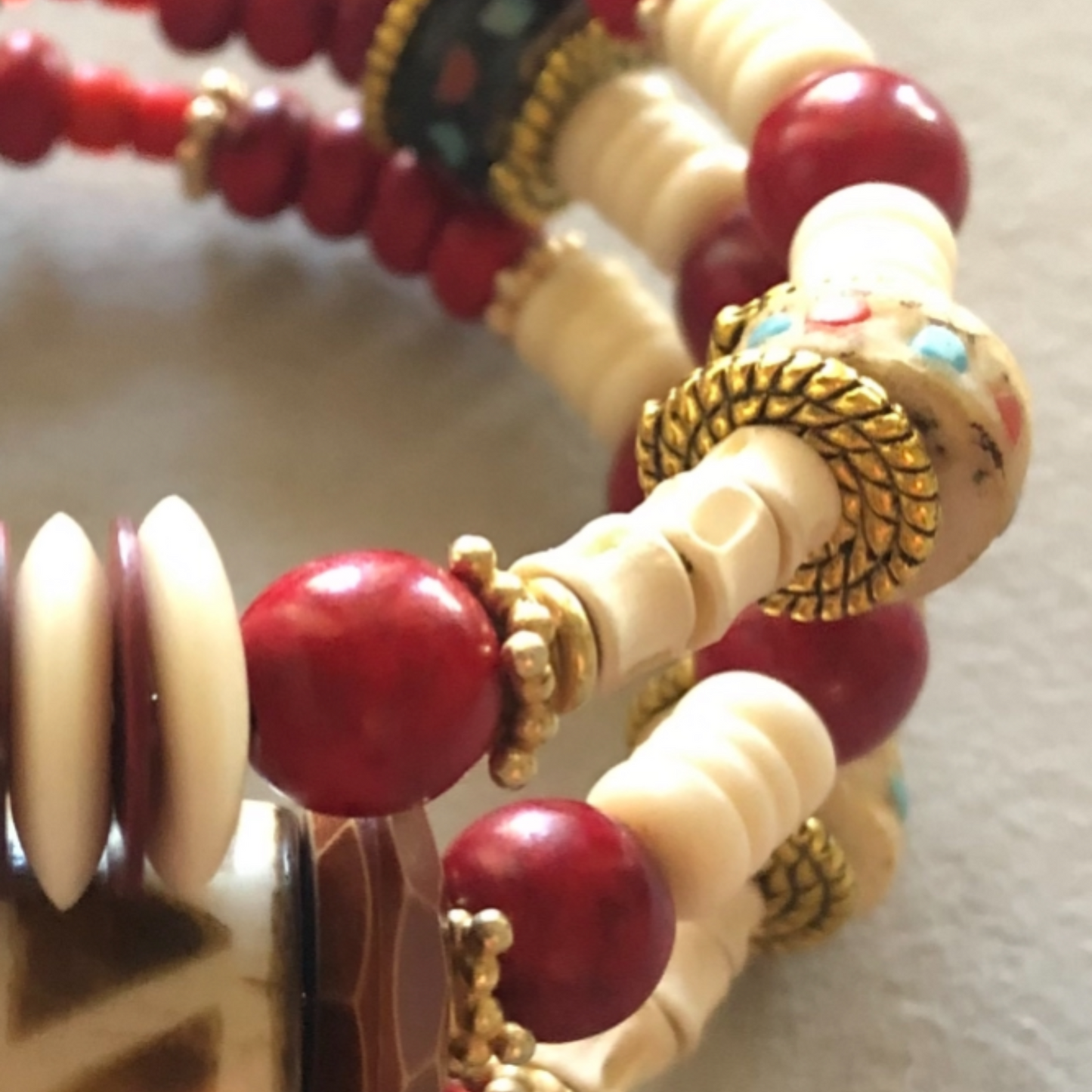 Three wrap bracelet with African-style hand-painted ceramic bead, bold red and gold spacers, cream bone spacers, and shiny textured copper flat spacers.